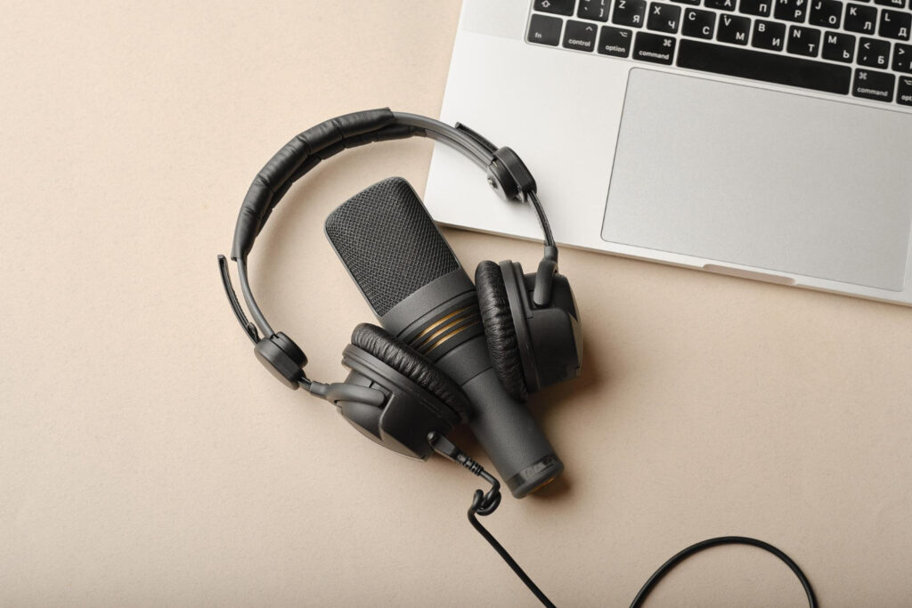 Nell'immagine un microfono, un paio di cuffie e un laptop, la strumentazione base per realizzare un podcast - Smart Marketing