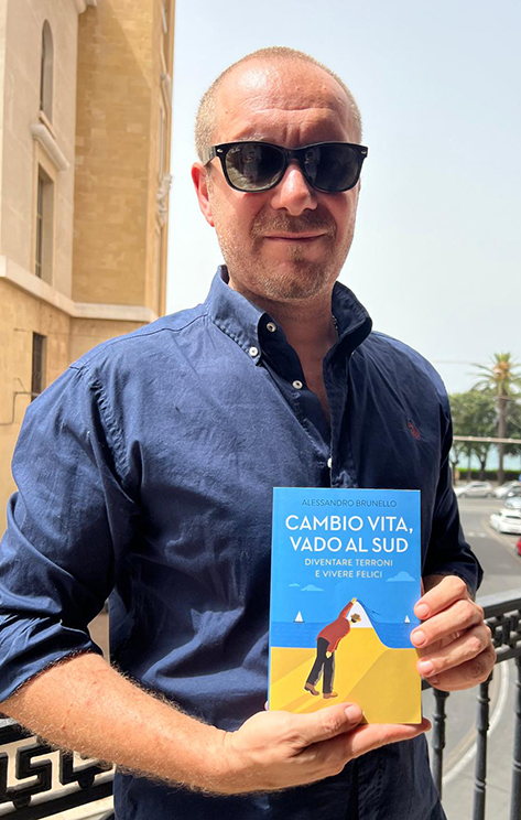 Nell'immagine lo scrittore Alessandro Brunello con una copia del suo libro "Cambio vita, vado al Sud" - Smart Marketing