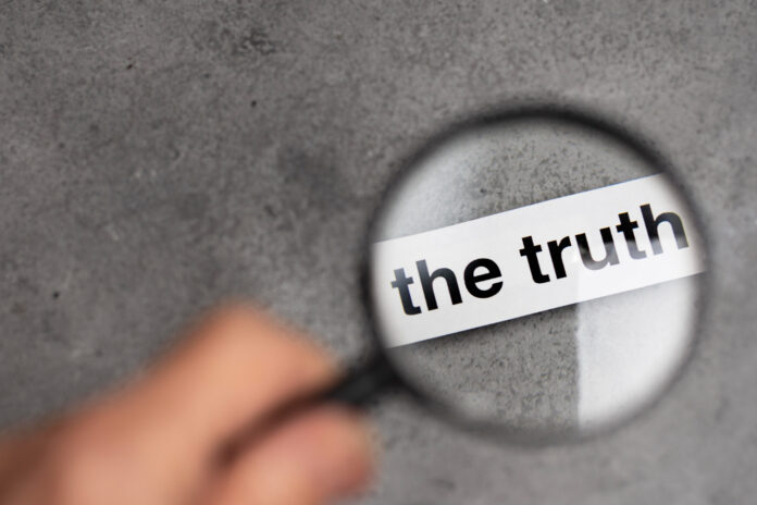 Nell'immagine una lente di ingradimento mette in risalto la parola "the truth" su di una superfice grigia, Meta fact-checking - Smart Marketing